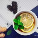 Immune Boosting Lemon Ginger Tea Detox Recipe ginger tea in a white mug with lemon slices and a sprig of mint for morning detox